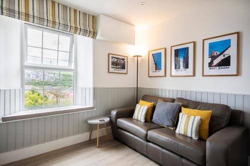 a living room with a couch and two windows at Seafarers - Coastguard Cottage with sea views, garden and parking in Mevagissey