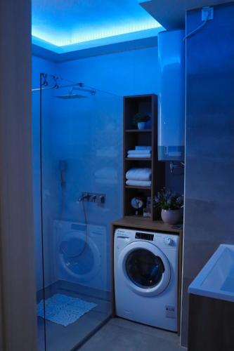 a bathroom with a washing machine and a blue light at 'NAP' apartment in Osijek
