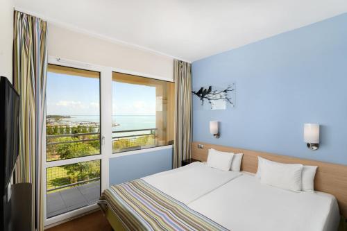 sypialnia z łóżkiem i dużym oknem w obiekcie Danubius Hotel Marina w Balatonfüred