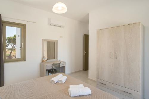 a white bedroom with two towels on a bed at Hercules house pyrgaki paros in Drios