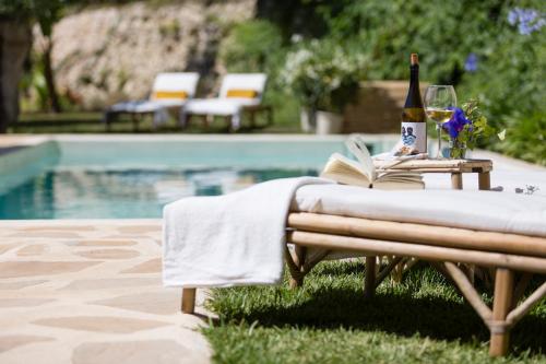 a table with a bottle of wine and a book next to a pool at Villa Riu Blanc in Benissa