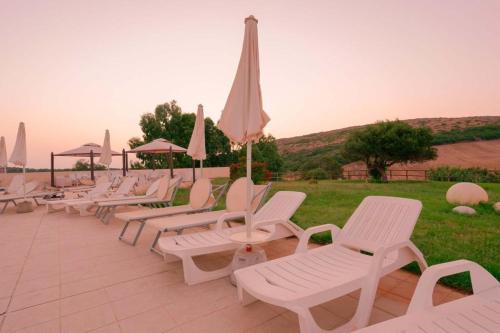 a row of white chairs and umbrellas on a patio at Capofrascaresort in Sant' Antonio di Santadi