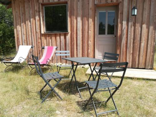 uma mesa de piquenique e cadeiras em frente a uma cabana em Hébergement naturel em Sigonce