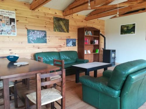 ein Wohnzimmer mit grünen Möbeln und einer Holzwand in der Unterkunft Hébergement naturel in Sigonce
