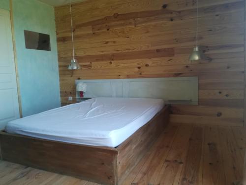 uma cama num quarto com paredes e pisos em madeira em Hébergement naturel em Sigonce
