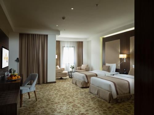 a hotel room with three beds and a living room at Retaj Inn Al Wakrah in Al Wakrah
