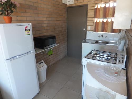 a kitchen with a white refrigerator and a stove at Sunrise Units in Hervey Bay