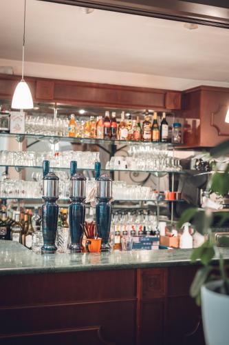a bar with a counter with bottles and glasses at Logis Hôtel Vuillot in Cuiseaux