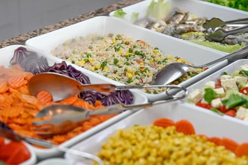a buffet of different types of food with spoons at Hotel Pinos Playa in Cala Santanyi