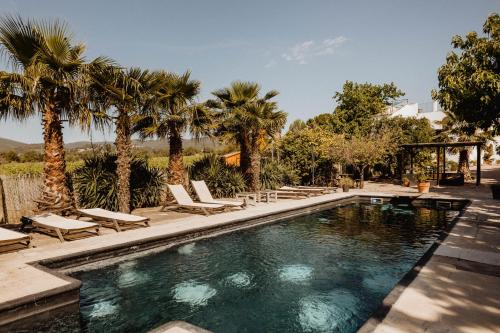 a swimming pool with lounge chairs and palm trees at Cal Pau Cruset in Torrellas de Foix