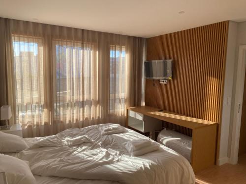 a bedroom with a bed and a desk and windows at Altamira GB in Estarreja