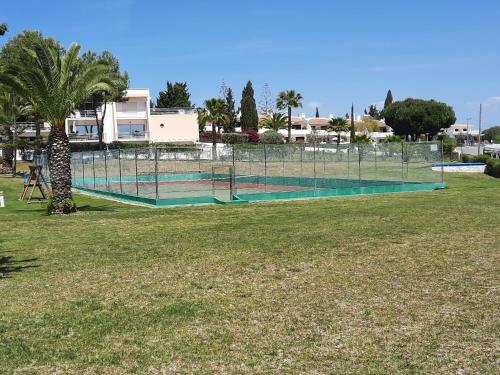 a tennis court in a park with a palm tree at Armação De Pêra Brightness 2 With Pool by Homing in Armação de Pêra