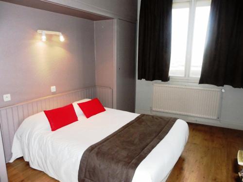 a bedroom with a bed with two red pillows at Hôtel Du Port in Les Sables-dʼOlonne