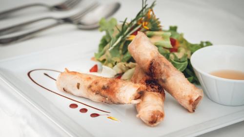a plate with carrots and a salad and a cup of tea at Logis Hôtel Vuillot in Cuiseaux