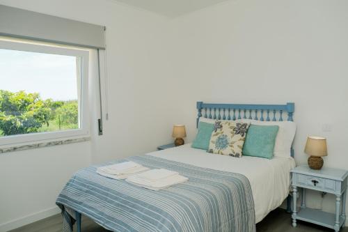 a bedroom with a bed with a window at Like-Home-T3 House-garden, sea view, beach in Casais de São Lourenço