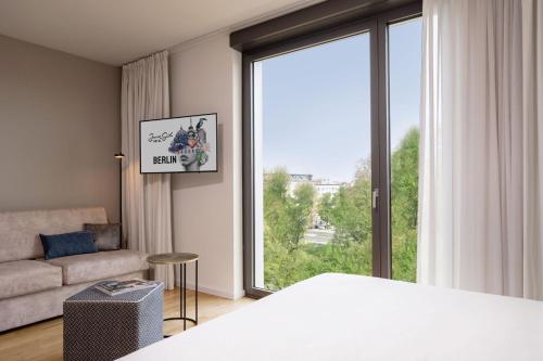 a bedroom with a bed and a couch and a large window at June Six Hotel Berlin City West in Berlin