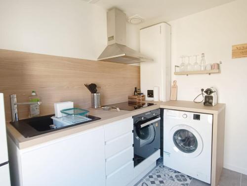 uma cozinha com uma máquina de lavar roupa e um lavatório em Immeuble Centre Ville em Saint-Médard-de-Guizières