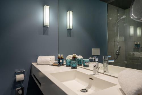 ein Badezimmer mit einem weißen Waschbecken und einem Spiegel in der Unterkunft June Six Hotel Berlin City West in Berlin