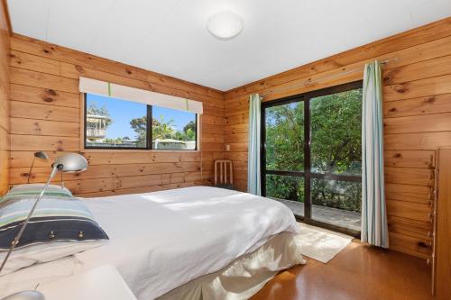 um quarto com uma cama e uma grande janela em Karaka Bach - Mangawhai Heads Holiday Home em Mangawhai