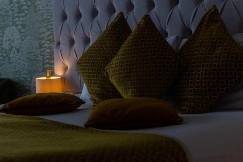 a bed with four pillows and a candle on it at Hatherley Manor Hotel & Spa in Gloucester