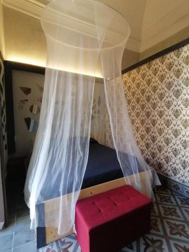 a bed with a white curtain and a red bench at L'Antico Palazzo rooms in Catania