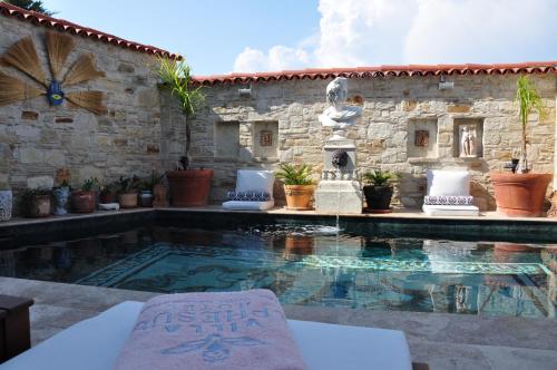 a swimming pool in front of a stone building with a fountain at Villa Ephesus Hotel in Kusadası