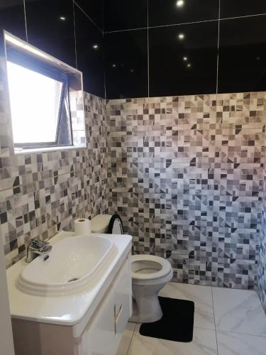a bathroom with a sink and a toilet and a window at National Lodge in Benoni