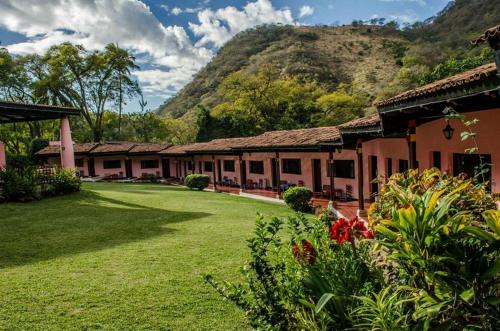 a building with a green yard with a mountain in the background at Hotel Agua Blanca in San José Purúa