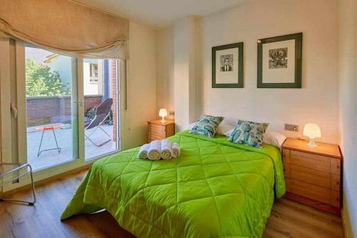a green bed in a room with a window at Apartamento con gran terraza en Girona in Girona