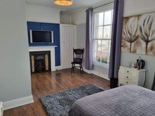 a room with a bed, chair and a fireplace at Y Castell in Caernarfon
