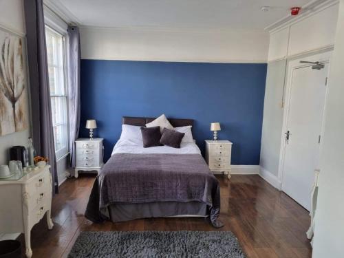 a bedroom with blue walls and a bed with pillows at Y Castell in Caernarfon