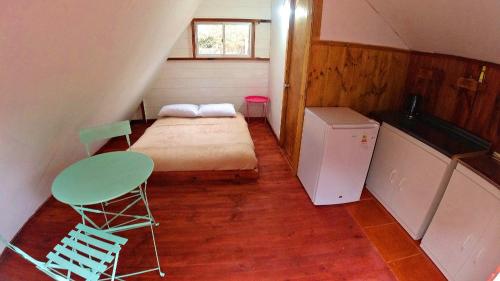 Habitación pequeña con cama, mesa y nevera. en Lodge Spa Melipilla en Melipilla