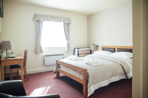 a bedroom with a bed and a desk and a window at The Jolly Drover in Liss