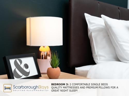 a lamp on a table next to a bed at Scarborough Stays - Ashville Lodge - 5 Bedroomed house - Sleeps 9 in Scarborough