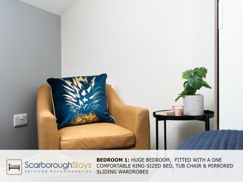 a yellow chair with a blue pillow in a room at Scarborough Stays - Ashville Lodge - 5 Bedroomed house - Sleeps 9 in Scarborough