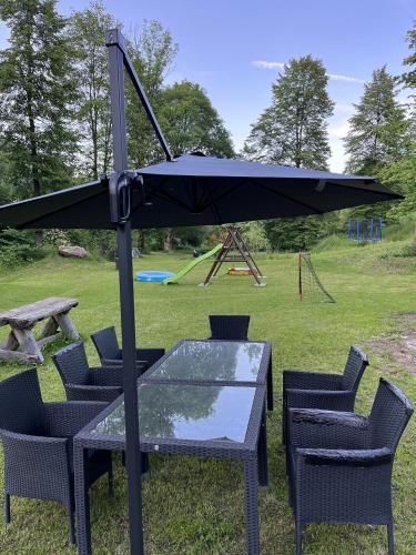 a table and chairs with an umbrella on the grass at CHALUPA NAD POTOKEM in Zlaté Hory
