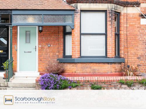 uma casa de tijolos com uma porta branca e janelas em Scarborough Stays - Ashville Lodge - 5 Bedroomed house - Sleeps 9 em Scarborough
