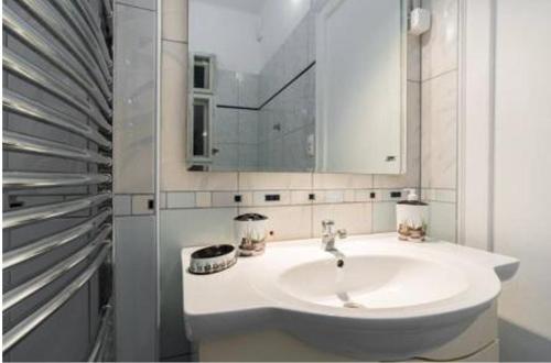 a white bathroom with a sink and a mirror at Monolit Budapest Center Guesthouse in Budapest