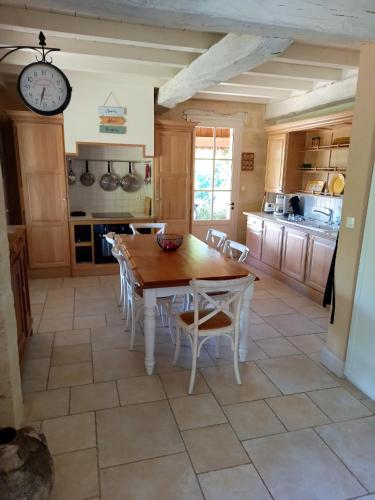 une cuisine avec une table, des chaises et une horloge dans l'établissement Maison charmante avec jacuzzi à Saint-Ciers-de-Canesse, à Saint-Ciers-de-Canesse