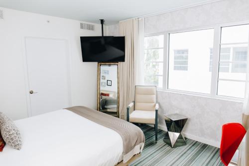 a bedroom with a bed and a chair and a tv at Uma House by Yurbban South Beach in Miami Beach