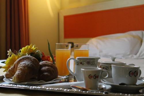a breakfast table with a tray of food and orange juice at Hotel Cristal Eboli in Eboli