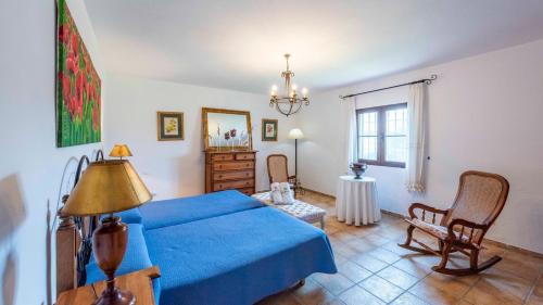 um quarto com uma cama azul e uma cadeira em Casa Rural Cortijo Picuales Torrox by Ruralidays em Torrox