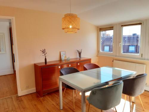 une salle à manger avec une table et des chaises en verre dans l'établissement Appartement Malo les Bains à deux pas de la plage, à Dunkerque