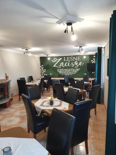 uma sala de jantar com mesas e cadeiras e uma parede verde em Leśne Zacisze em Weremień