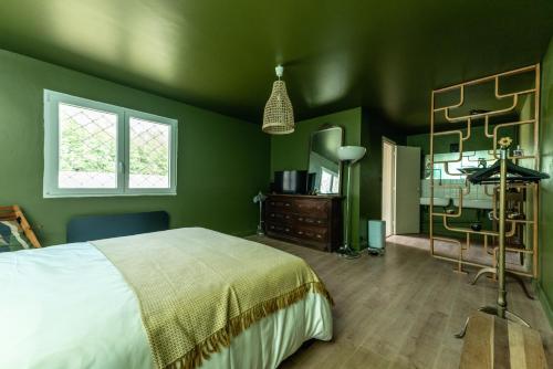 a bedroom with green walls and a bed and a mirror at Chambre d'hôte près Bordeaux in Bourg-sur-Gironde