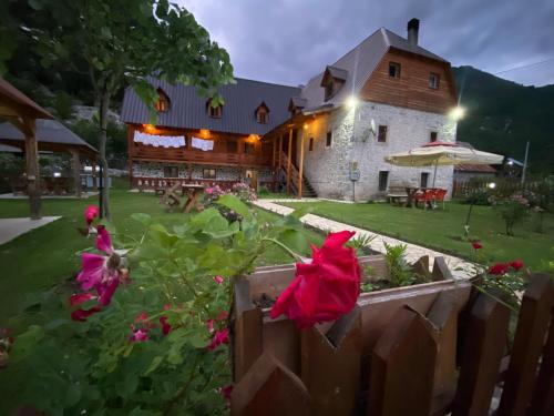 a house with a fence and flowers in the yard at Guesthouse Prrockaj Theth in Theth
