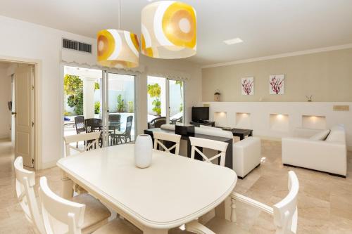 comedor y sala de estar con mesa blanca y sillas en Villa 10.3, en Corralejo