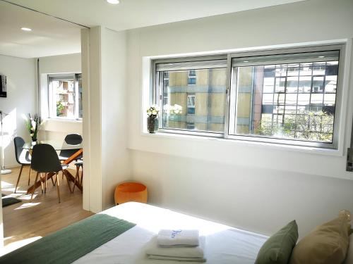 a bedroom with a bed and two windows and a table at OportoView Prestige Apartment in Porto