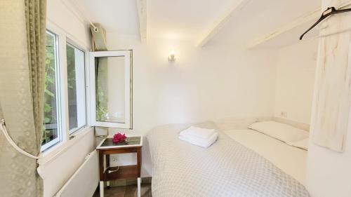 a white bedroom with a bed and a window at The Bungalow in Braşov