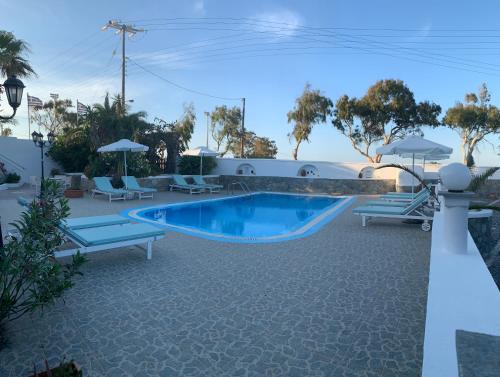 a swimming pool with lounge chairs and a resort at Villa Ilios in Fira